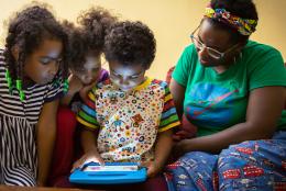 A photo of parent and children using tablet